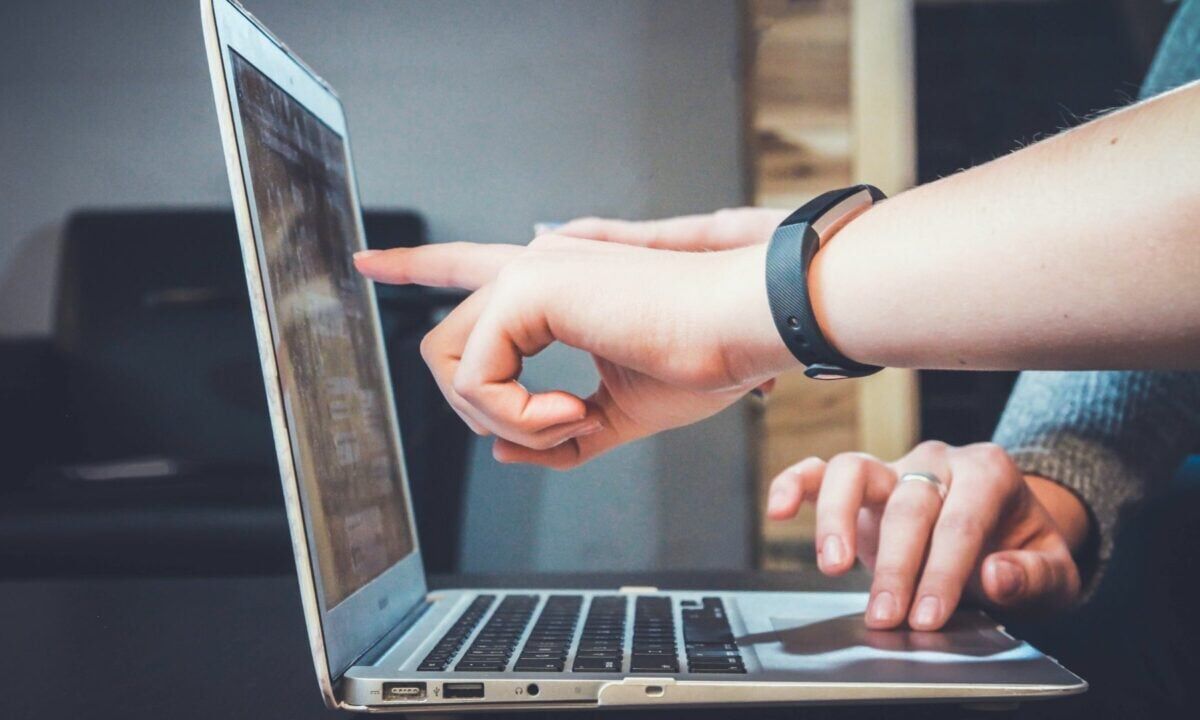 Two agents work together on a laptop discussing potential real estate blog ideas that may generate leads and improve their marketing ROI