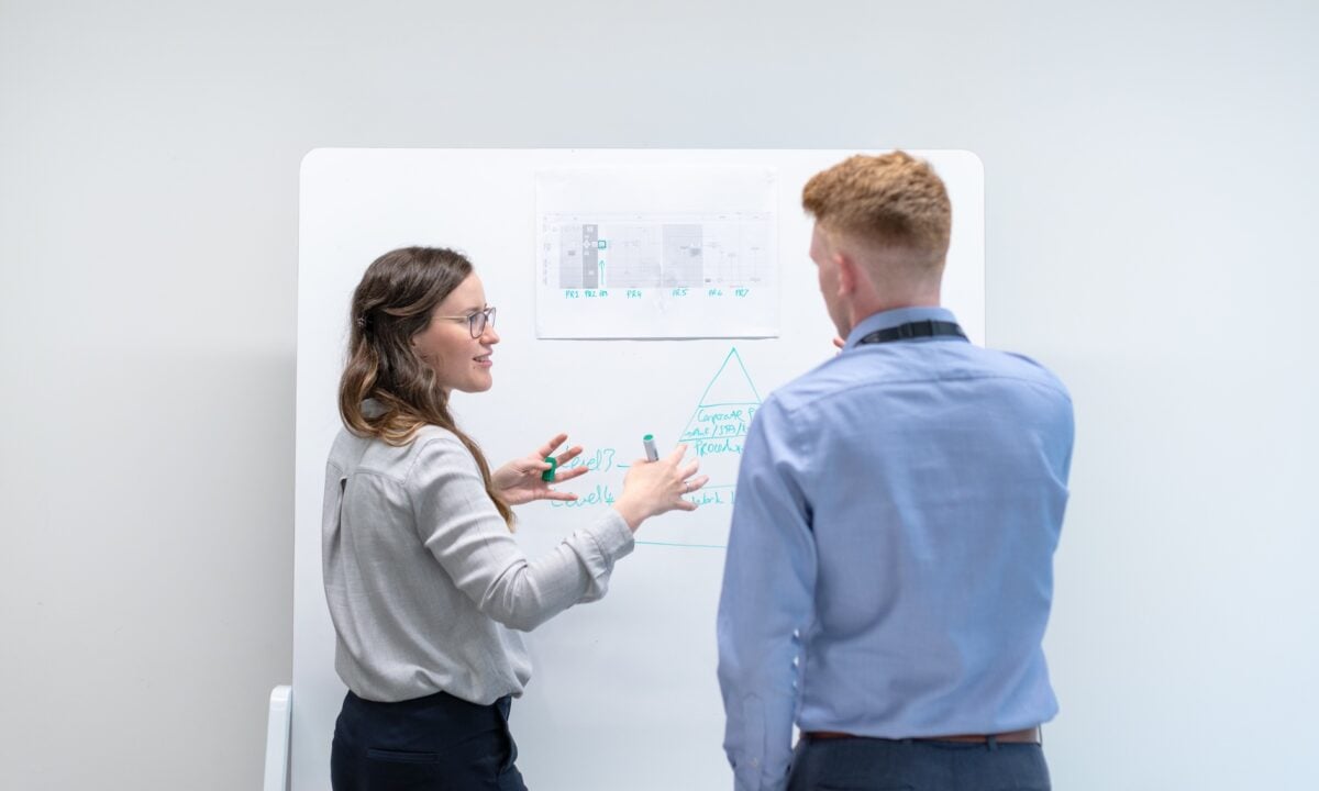 An engineer stands in front of a whiteboard, explains to a real estate professional how he can use ai in email marketing