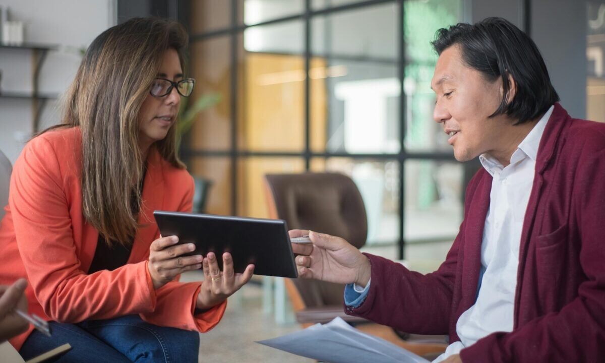 A real estate agent looking over a private listing with their client on a smart tablet, following the rules of the National Association of Realtors' Clear Cooperation Policy